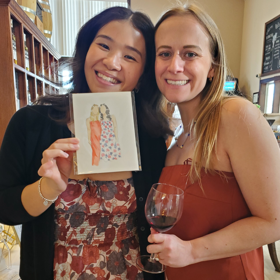 Two bridal shower guests smiling and holding their finished custom watercolour portrait