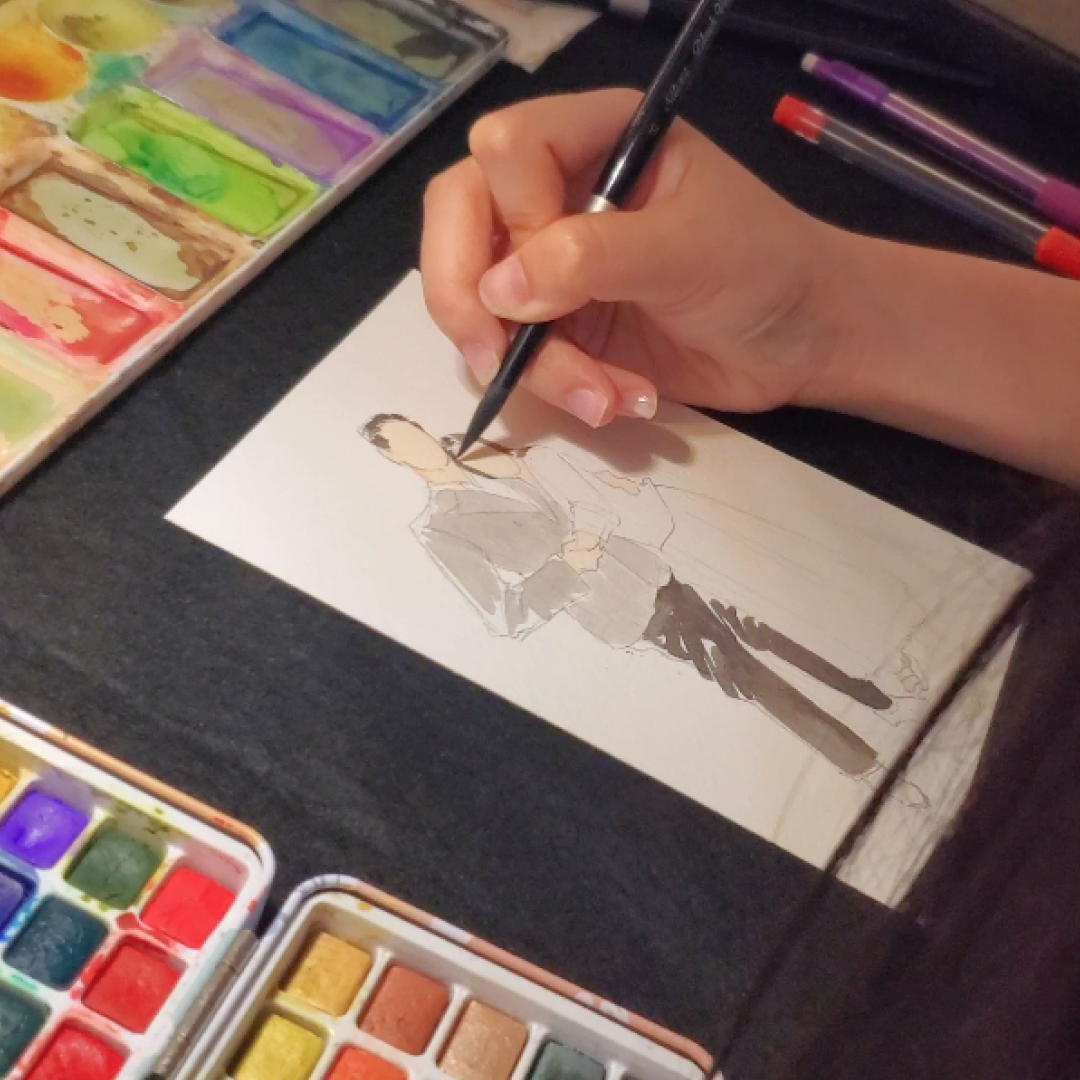 Close-up of a live artist painting a guest portrait in watercolour during a wedding
